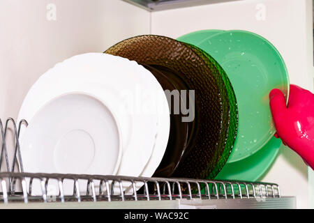 Dish dryer in the closet. White background. Plates of different colors. Cleaning, cleanliness Stock Photo