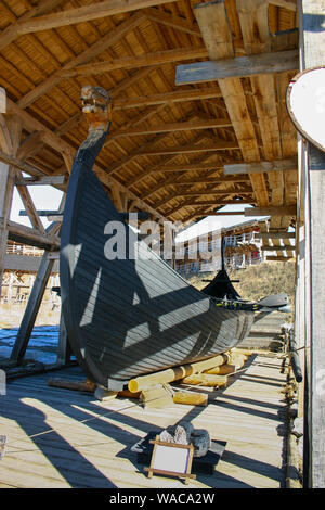 Ancient Scandinavian wooden ship of the Vikings Drakkar under a canopy in the open-air museum. Drakkar with hand-carved dragon's head on the nose, oar Stock Photo