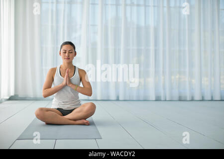 Focused young woman meditating while practicing yoga. Stock Photo