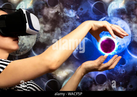 A woman is looking through virtual reality at space. Space background Stock Photo