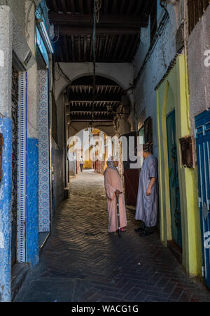 Local man and woman talking in the alleyway in Tangier, Morocco Stock Photo
