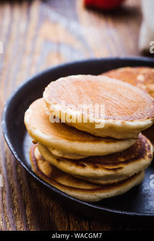 Cooking healthy breakfast or brunch, favorite morning meal. Homemade pancakes in rural pan, fresh summer dessert with strawberries on rustic wooden ta Stock Photo