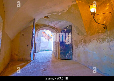SALZBURG, AUSTRIA - FEBRUARY 27, 2019: The stone corridor with shabby walls and old wooden doors leading to the courtyard of Hohensalzburg Castle, on Stock Photo