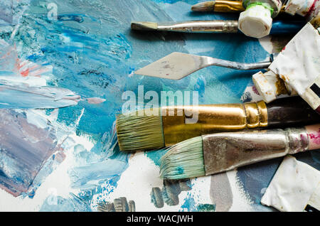 Artist paint brushes on wooden palette. Texture mixed oil paints