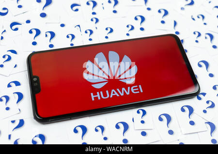 HUAWEI logo on the HUAWEI smartphone and a lot of paper question marks around. The conceptual photo about future of the tech giant in the US. Stock Photo