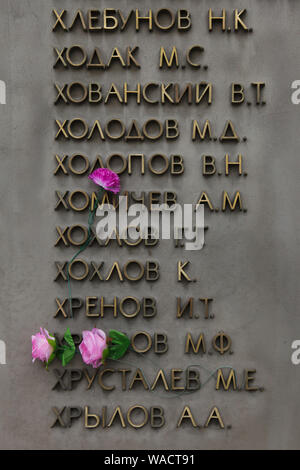 Plastic flowers placed between the names of Soviet soldiers on the ground of the memorial to the fallen during World War II at Shirokorechenskoye Cemetery in Yekaterinburg, Russia. Stock Photo