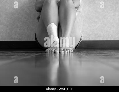 Black and white version of Athlete with an ankle sprain sitting down for a break Stock Photo