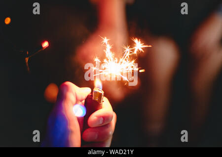 Cropped male hand igniting sparkler held by woman Stock Photo