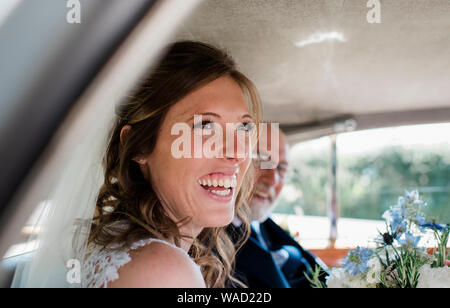 a bride laughing in her car on her wedding day Stock Photo