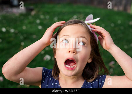 A small girl on a breezy day holds a flower blossom on head as a hat Stock Photo