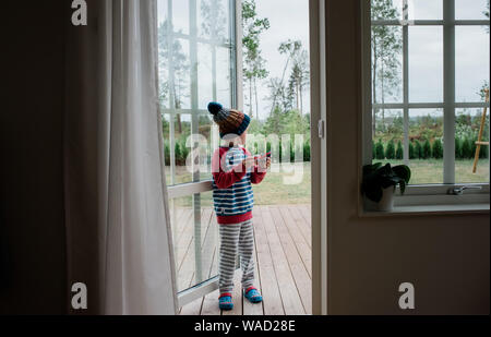 boy stood in doorway playing with aeroplane at home Stock Photo