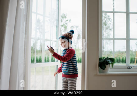 young boy playing with aeroplane in the doorway at home Stock Photo