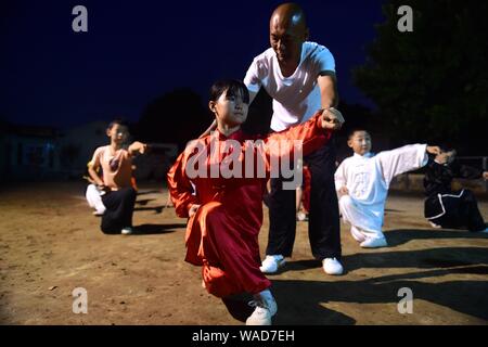 A Chinese child practices Chinese martial arts or kungfu directed by Chen Honglin, a well-known local practitioner, to maintain fitness during the sum Stock Photo