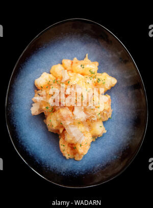 Shrimps cooked in Asian style in batter with sweet-sour sauce and bonito tuna, isolated on black background Stock Photo