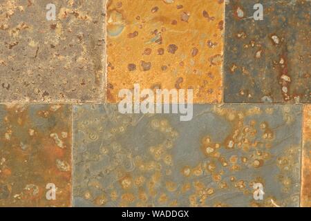 Rust colored square flagstones on a wall. Texture detail close up. Stock Photo