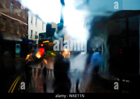 Passenger's view of blurry pedestrians out of bus window on wet rainy day with water running down the bus window pane Stock Photo