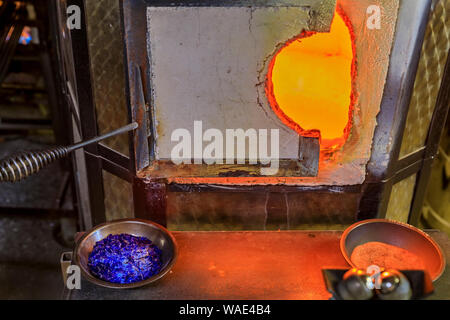 Glass blowing furnace and table with with crushed glass and tools at a glass maker's workshop set up for the traditional glass blowing process Stock Photo