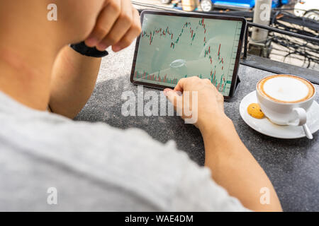 Asian freelancer looking at financial candlestick graph on tablet Stock Photo