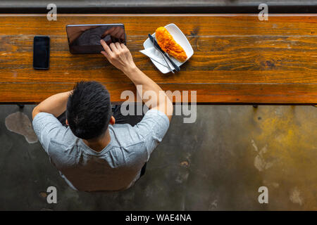Top view of Asian millennial using tablet while having breakfast Stock Photo