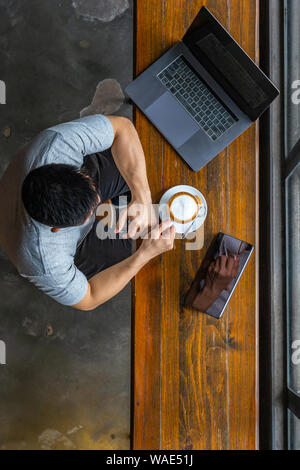 Vertical photo of muscled freelancer using laptop and drinking coffee Stock Photo