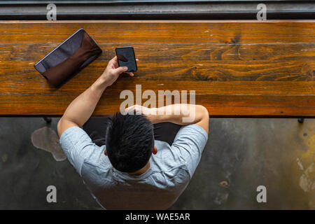 High angle view of Asian man using cellphone and tablet Stock Photo