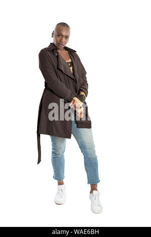 Black African American fashion model with bald hairstyle confidently posing with a coffee brown colored jacket for fall collection.  Depicts fashion d Stock Photo