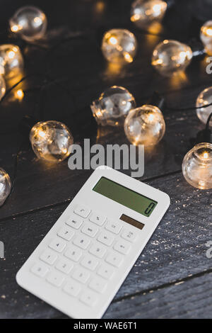 calculator on wooden desk surrounded by lightbulb string lights ...