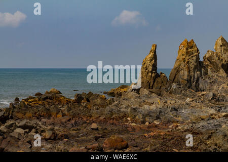 Big rocks on the shore in India with blue sea and mist on the ocean. Natural landscape of dark day.Summer travel concept. Stock Photo