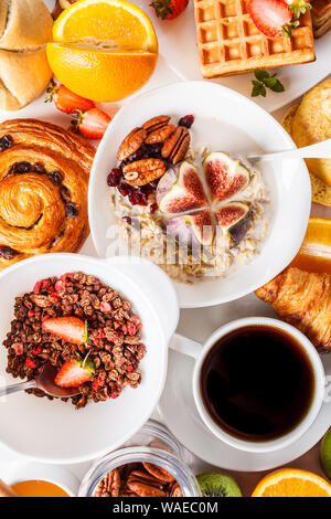 Breakfast table with oatmeal, granola, waffles, croissants and fruits. White background.