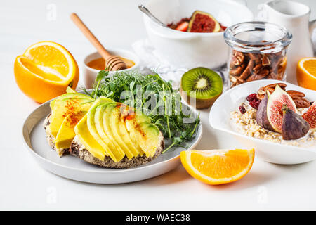 Vegan breakfast table with avocado toast, oatmeal, fruit, on a white background. Stock Photo