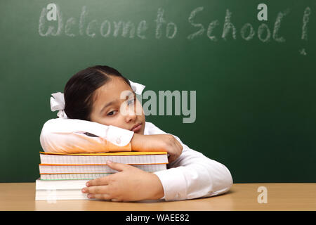 Indian schoolgirl looking tired while studying Stock Photo