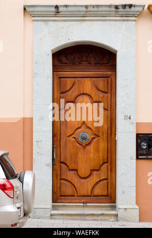 Car parked on street outside wooden front door of house home exterior, Oaxaca City, Oaxaca, Mexico Spanish colonial architecture details Stock Photo