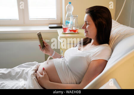 Risk pregnancy, pregnant woman lies in hospital and makes selfie, Carlsbad, Czech Republic, Europe Stock Photo