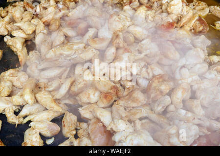 Fast street-food - smoked chicken slices  fried  in big iron black frying pan. Snapshot style image Stock Photo
