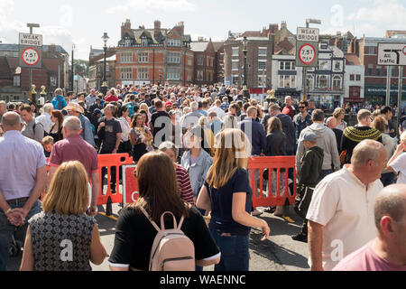 Crowds of people crossing the swing bridge during Whitby folk festival, North Yorkshire, England, UK Stock Photo