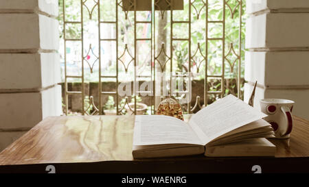 Coffee and book by window on a sunday morning. Reading book in morning sunlight. Hygge summer mood. Holidays, leisure, literature and relaxation conce Stock Photo