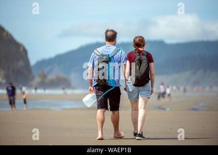 Young couple are walking along the shore of the Northwest Pacific Ocean holding hands and breathing healthy fresh sea air to strengthen immunity and s Stock Photo