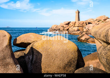 The Ploumanac'h lighthouse, named Mean Ruz, on the Pink Granite Coast in Perros-Guirec, northern Brittany, with large granite rocks in the foreground. Stock Photo