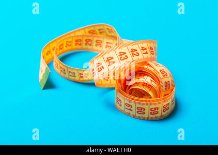 Perspective view of spiral measuring tape on blue background. Close up of slimming concept. Stock Photo