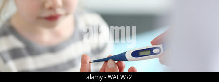 Female hand holding thermometer measuring sick little girl Stock Photo