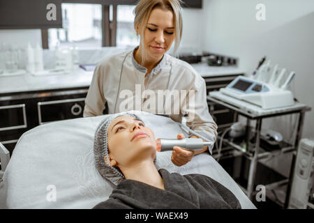 Female cosmetologist making oxygen mesotherapy to a woman at the luxury beauty salon. Concept of a professional facial treatment Stock Photo