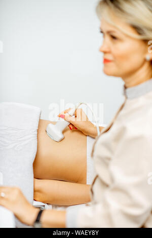 Female doctor performs ultrasound examination of a women's pelvic organs or diagnosing early pregnancy at the medical office Stock Photo