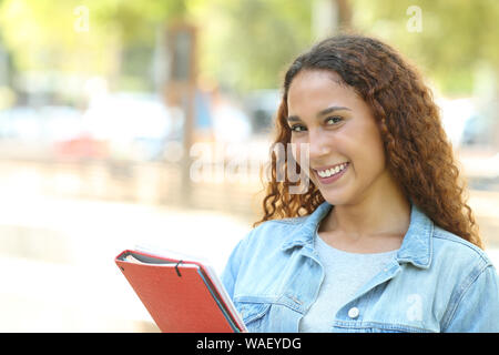 Happy mixed race student posing looking at camera standing in a park Stock Photo