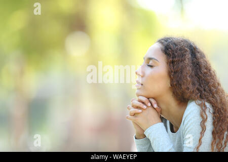Side view portrait of a serious mixed race woman meditating and breathing fresh air outdoors in a park Stock Photo