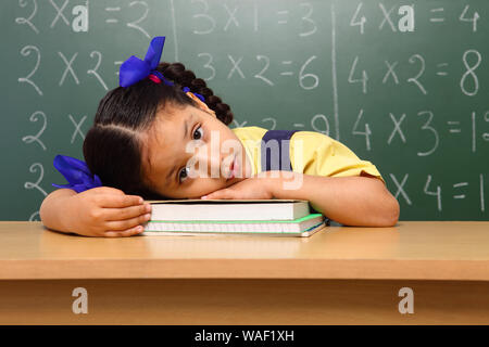 Schoolgirl looking tired while studying Stock Photo