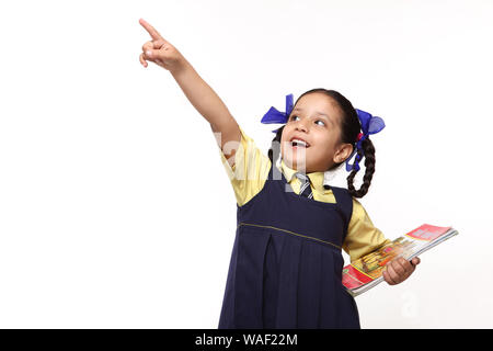 Indian schoolgirl holding books and showing something Stock Photo