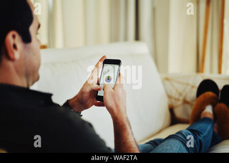 Close-up of a man sitting on sofa using smartphone Stock Photo