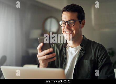 Man smiling while texting messages on mobile phone Stock Photo