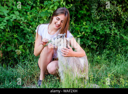 Woman play cute goat. Veterinarian occupation. Treating animals at farm. United with nature. Animals law. Girl and goat green grass. Farm and farming concept. Village animals. Protect animals. Stock Photo