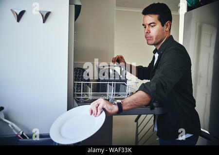 Man loading dishwasher in kitchen Stock Photo